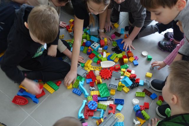 dzieci układają klocki Lego na podłodze