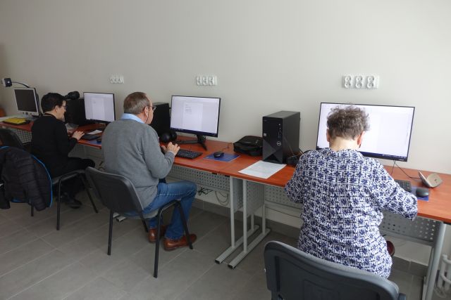 dwie kobiety i mężczyzna siedzą przy komputerach