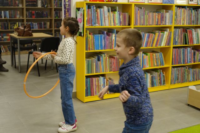 dzieci kręcą hula hop, w tle regały z książkami