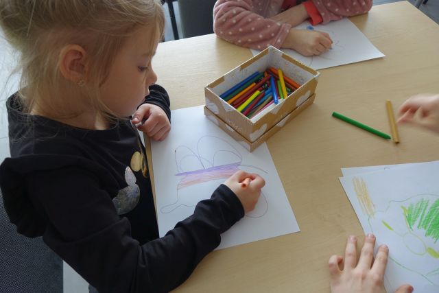 dzieci malują kredkami na kartkach motyle