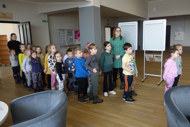 dzieci i 2 opiekunki stoją w holu biblioteki