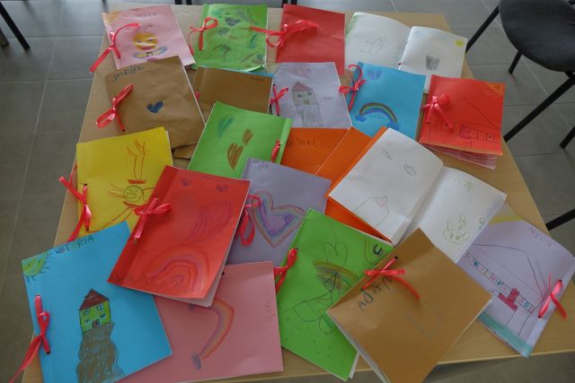 wykonane przez dzieci książeczki, zawiązane czerwonymi wstążkami