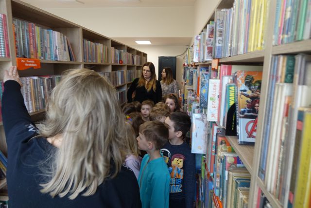 dzieci spacerują między regałami z książkami