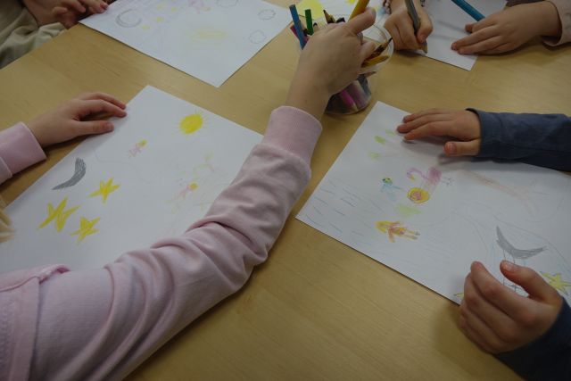 dzieci rysują na kartkach kredkami