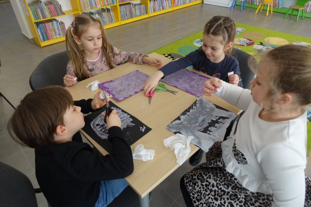 dzieci siedzą przy stolikach i malują niedźwiedzie na kartakch za pomocą pasty do zębów