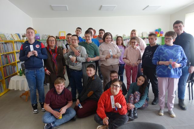 uczestnicy warsztatów pozują do zdjęcia z kobietą, w tle regały z książkami