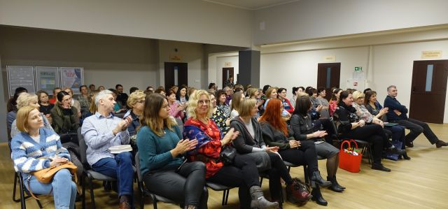 około 100 uczestników spotkania siedzi na krzesłach