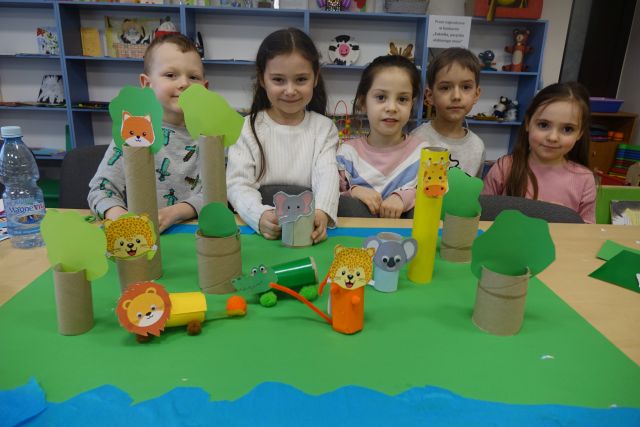 dzieci stoją za stołąmi, na stołąch wykonane przez nich zwierzęta