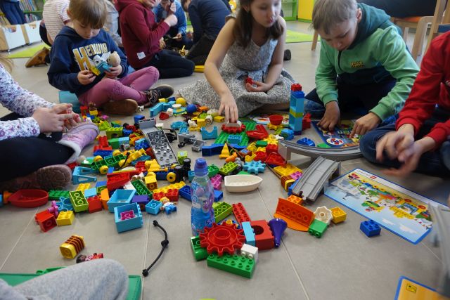 dzieci siedzące na podłodze układają klocki LEGO