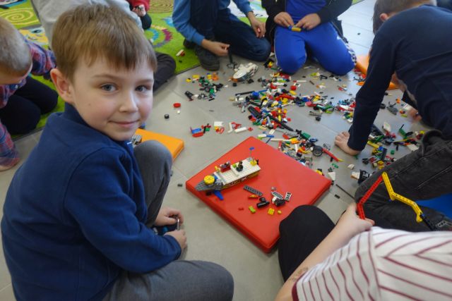 dzieci siedzące na podłodze układają klocki LEGO