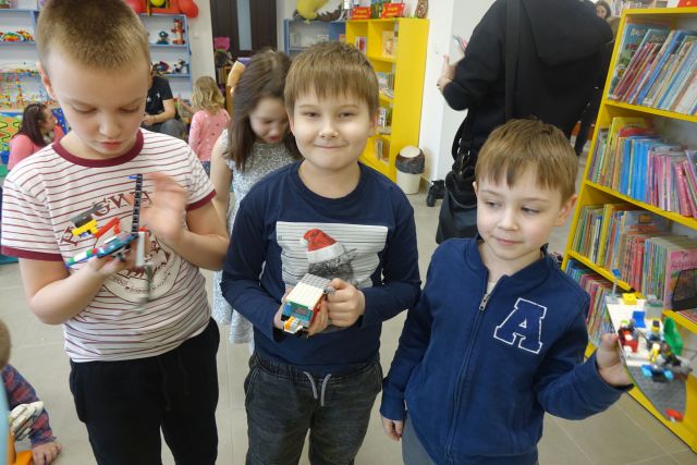 3 chłopców pokazuje zbudowane przez siebie pojazdy z klocków LEGO
