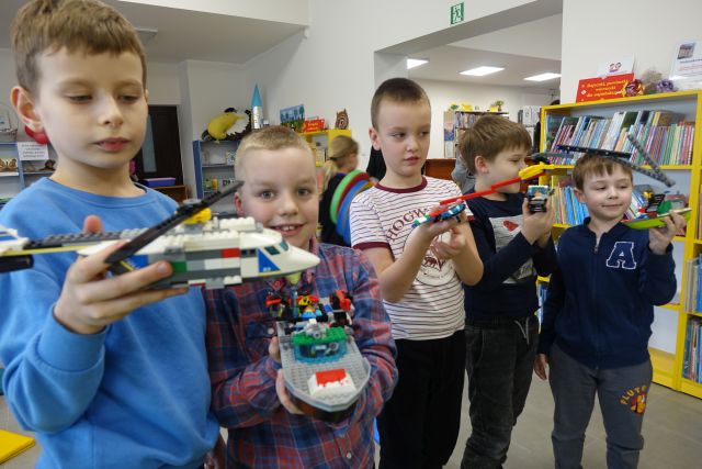 4 chłopców pokazuje zbudowane przez siebie pojazdy z klocków LEGO