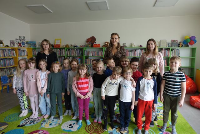 dzieci i trzy kobiety pozują do zdjęcia, w tle regały z książkami