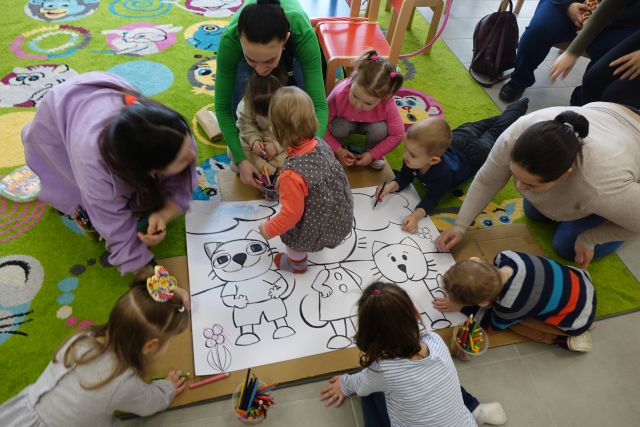 małę dzieci i rodzice zamalowują koty na dużej białe kartce