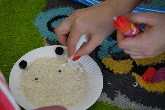 ryż na białym papierowym talerzyku, i ręka z kawałkiem papieru