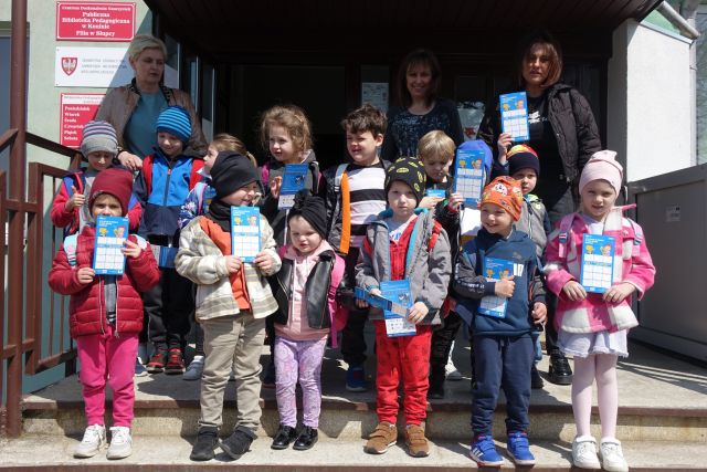 przedszkoalki pozują do zdjęcia z trzema kobietami na schodach przez wejściemdo biblioteki