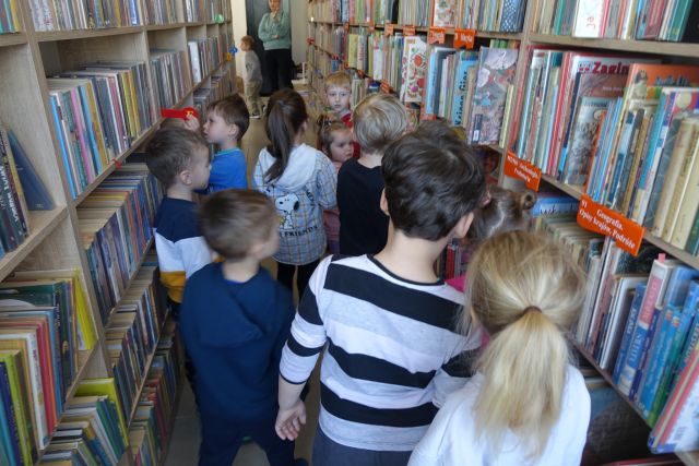 dzieci spacerują pomiędzy regałąmi z książkami
