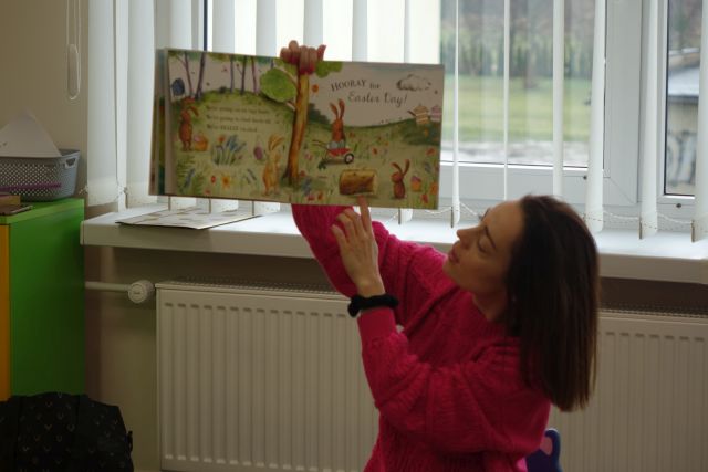 kobieta w różowej bluzce pokazuje książkę w języku angielskim