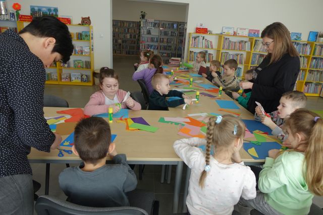 dzieci przy stołach wycinają tęcze