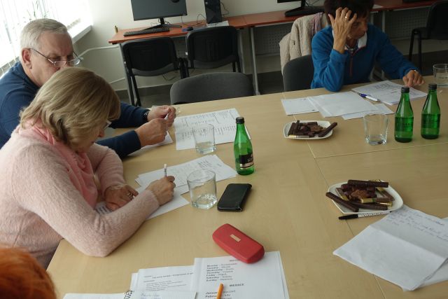 2 kobiety i 1 mężczyzna uczestniczą w zajęciach z języka angielskiego, na stołach kartki, długopisy, ptasie mleczko, woda, w tle sala komputerowa