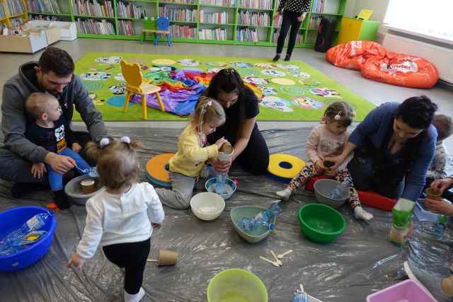 dzieci i rodzice siedzą na podłodze i robią z balonów i ryżu gniotki