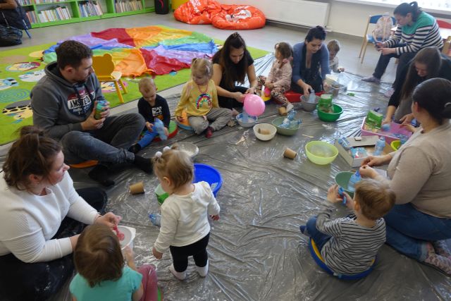 dzieci i rodzice siedzą na podłodze i robią z balonów i ryżu gniotki