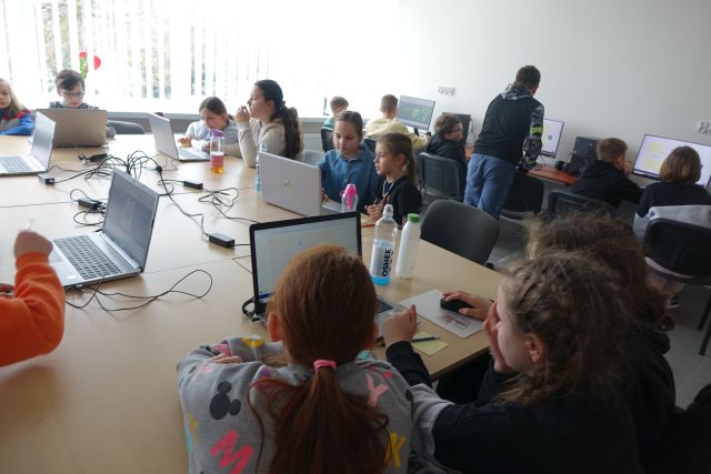 Młodzież pracuje przy laptopach i komputerach