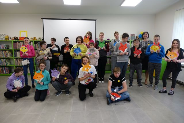 młodzież pozuje do zdjęcia z ilustratorką, w dłoniach trzymają wykonane przez siebie pyszczki lisów na papierowych talerzykach