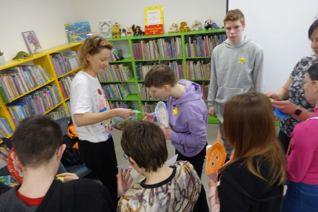 młodzież odbiera z rąk ilustratorki płyty, w tle regały z książkami
