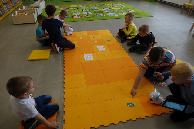 dzieci sterują robotami na pomarańczowej macie