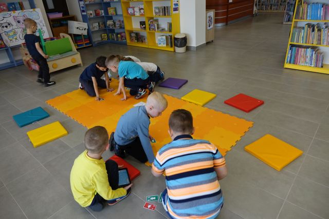 dzieci sterują robotami na pomarańczowej macie