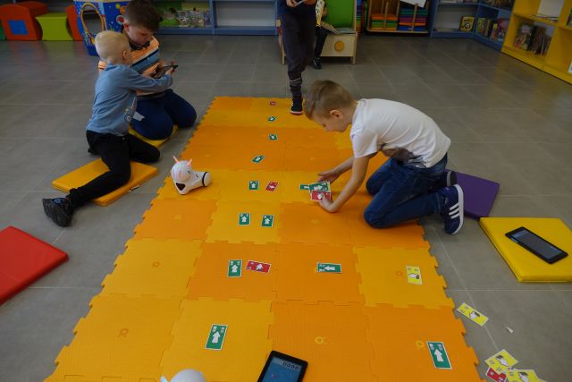 dzieci sterują robotami na pomarańczowej macie
