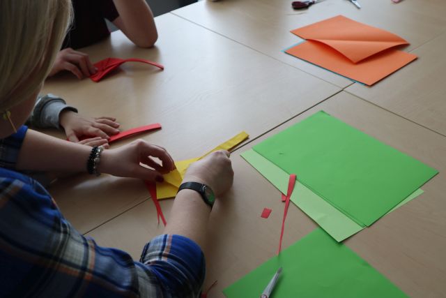 uczestnicy warsztatów wykonują koszyczki wielkanocne z papieru