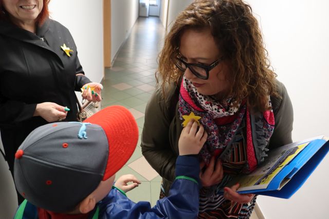 chłopiec przypina żółtego żonkila z papieru kobiecie