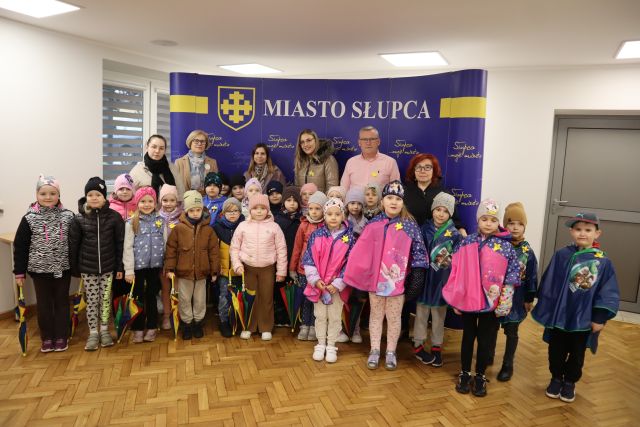 przedszkoalki pozują do zdjęcia z burmistrzerm, mają przypięte żółte żonkile z papieru