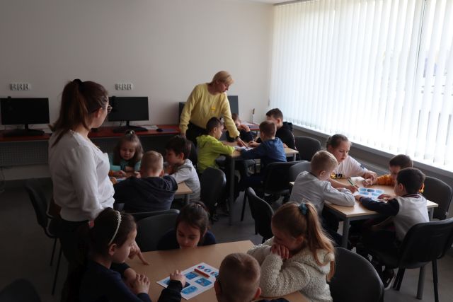 dzieci rozwiązują zadania siedząc przy stolikach