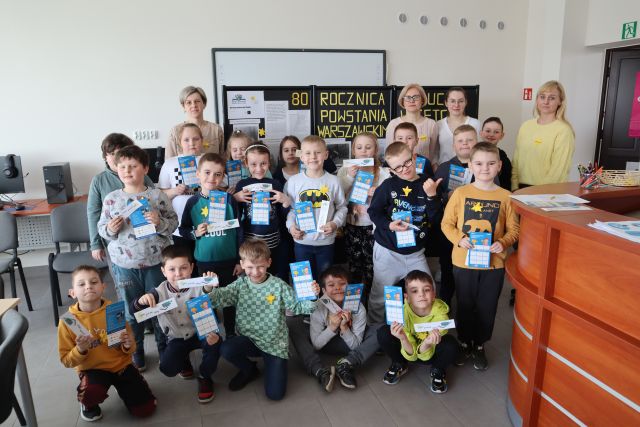 dzieci i nauczyciele pozują do zdjęcia z żonkilami przypiętymi do bluzek i zakłądkami