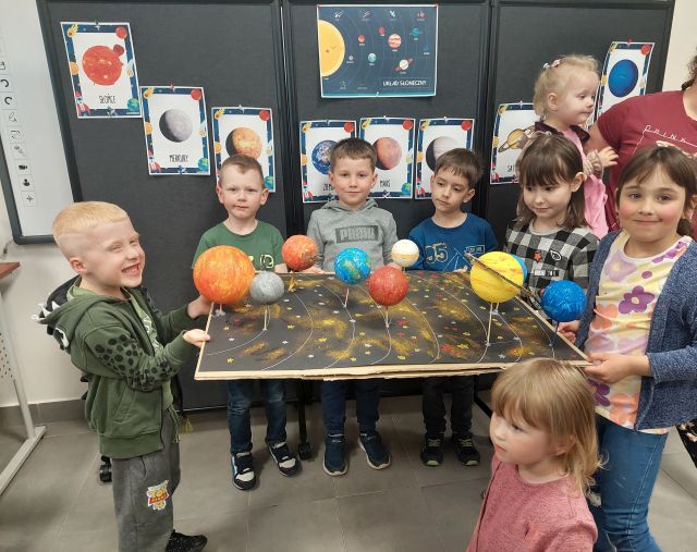 dzieci prezentują wykonaną przez siebie makietę z planetami