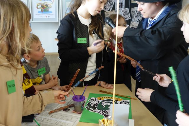 młodzież ozdabia patyki robiąc różdżki