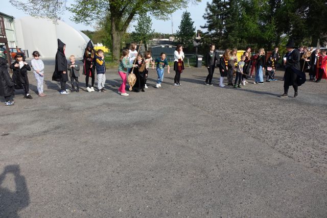 uczestnicy dnia harrego pottera biorą udział w wyścigach na miotłach na placu przed biblioteką