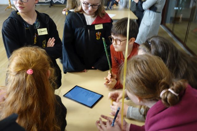 grupka młodzieży odpowiada na tabletach na pytania dotyczące książki o Harrym Potterze