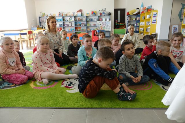 dzieci siedzą na kolorowym dywanie