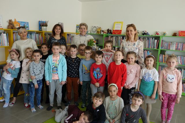 dzieci i 4 kobiety pozują do zdjęcia na tle regałów z książkami