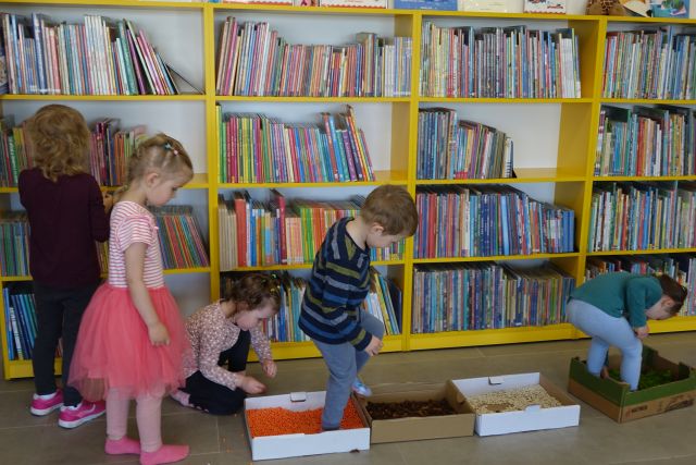 dzieci spacerują po ścieżce sensorycznej, w tle regały z książkami