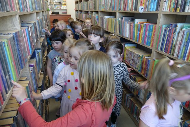dzieci spacerują między regałami z książkami