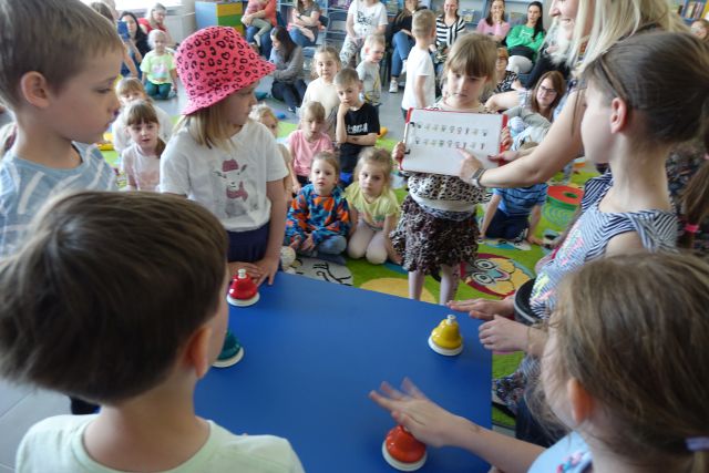 dziewczynka pokjazuje nuty dzieciom grającym na dzwoneczkach