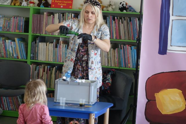 kobieta wlewa płyn do pojemniczka, w tle regały z książkami
