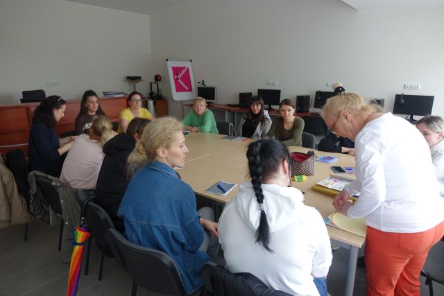 osoby dorosłe uczące się języka polskiego siedzxą przy stołach