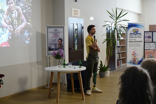 mężczyzna bez ręki stoi z mikrofonem i opowiada