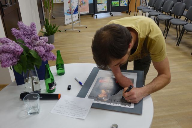 mężczyzna bez ręki podpisuje się na plakacie